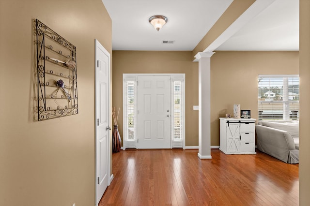 foyer with visible vents, baseboards, ornate columns, and hardwood / wood-style flooring