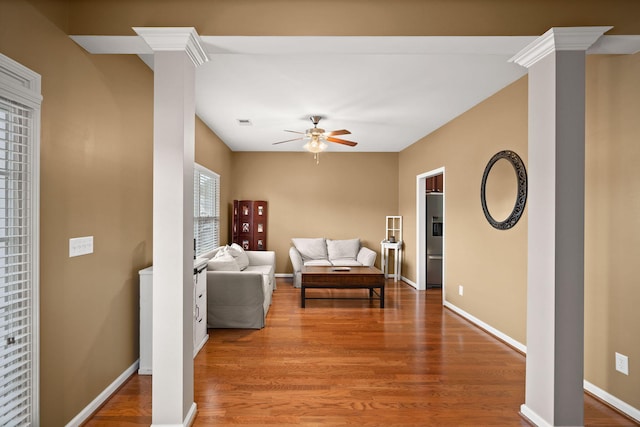 living room with visible vents, baseboards, ceiling fan, decorative columns, and wood finished floors