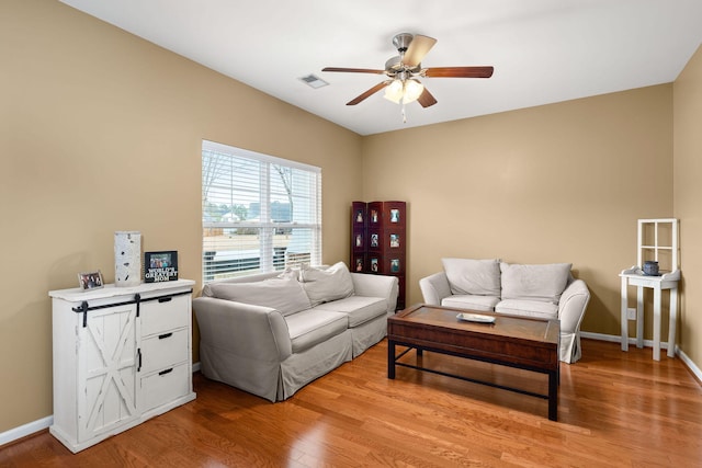 living area with visible vents, light wood-style floors, baseboards, and ceiling fan