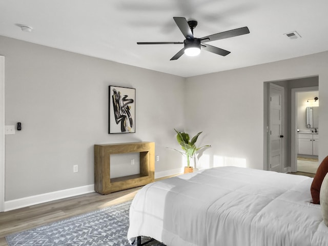 bedroom with dark wood-type flooring, ceiling fan, and ensuite bath