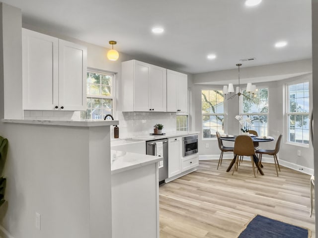 kitchen with pendant lighting, white cabinetry, light stone counters, tasteful backsplash, and stainless steel dishwasher