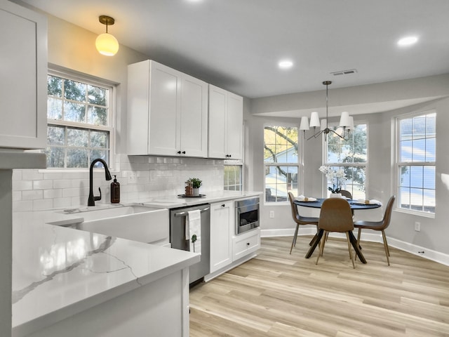 kitchen featuring hanging light fixtures, stainless steel appliances, sink, and white cabinets