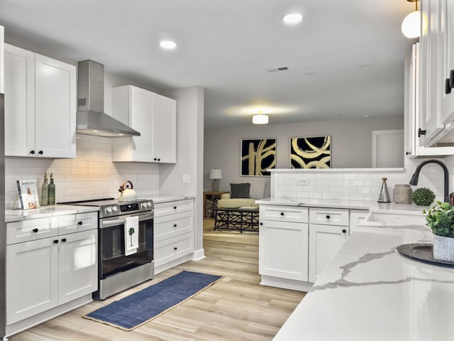 kitchen with white cabinetry, electric stove, light hardwood / wood-style floors, and wall chimney exhaust hood