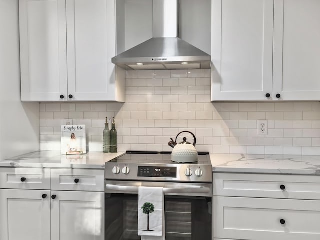 kitchen featuring white cabinetry, stainless steel range with electric stovetop, backsplash, and wall chimney exhaust hood