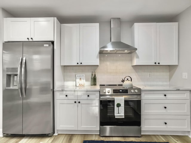 kitchen with stainless steel appliances, wall chimney range hood, white cabinets, and decorative backsplash