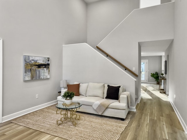 living room with a towering ceiling and light wood-type flooring