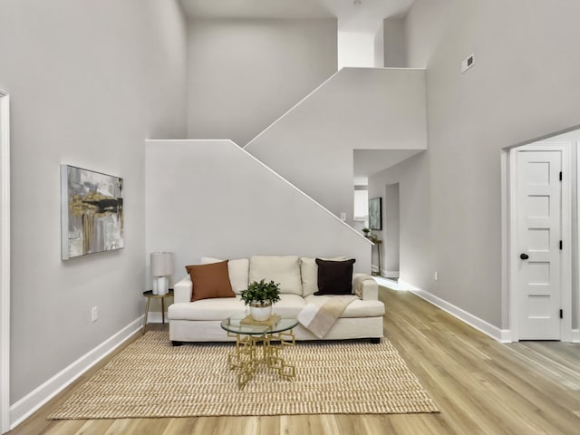 living room featuring wood-type flooring and a towering ceiling