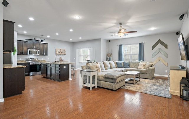 living room with hardwood / wood-style flooring, ceiling fan, and sink