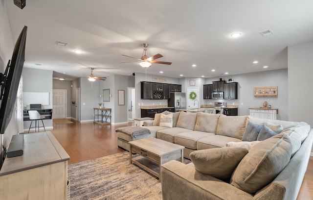 living room featuring ceiling fan, sink, and light wood-type flooring