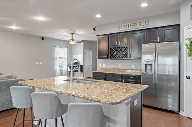 kitchen featuring an island with sink, sink, dark wood-type flooring, and stainless steel fridge with ice dispenser