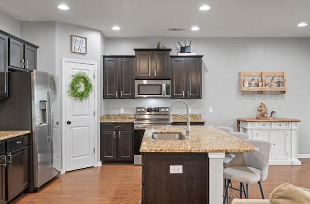 kitchen featuring dark brown cabinetry, stainless steel appliances, sink, and a center island with sink