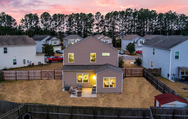 back house at dusk with central AC unit, a yard, and a patio