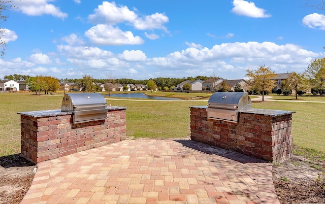 view of patio with a water view, area for grilling, and exterior kitchen