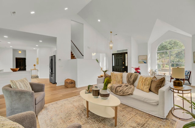 living room featuring light hardwood / wood-style flooring and high vaulted ceiling