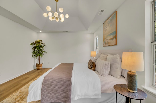 bedroom with hardwood / wood-style floors, a chandelier, and vaulted ceiling