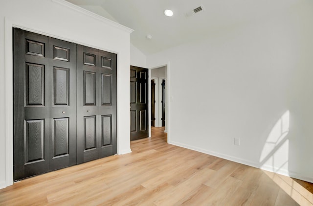 unfurnished bedroom with a closet, vaulted ceiling, and light hardwood / wood-style floors