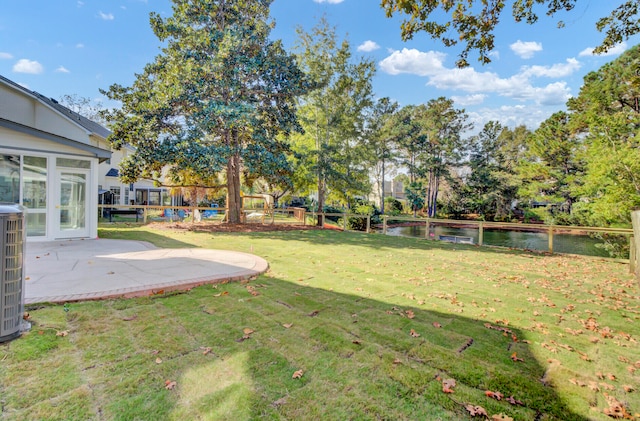 view of yard with cooling unit, a patio, and a water view