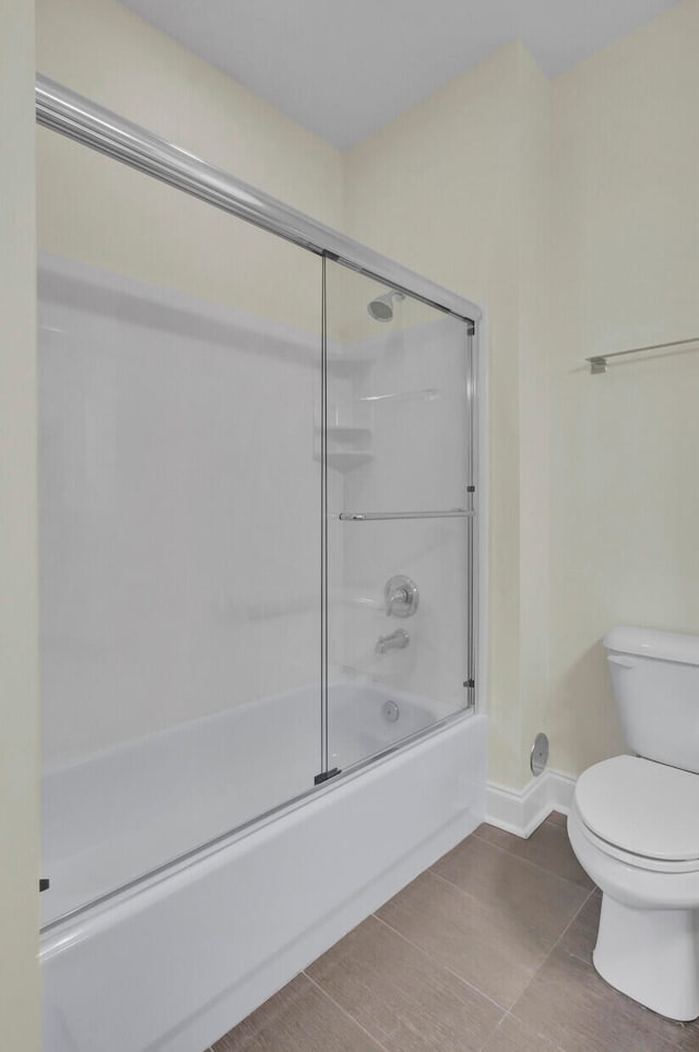 bathroom with bath / shower combo with glass door and toilet