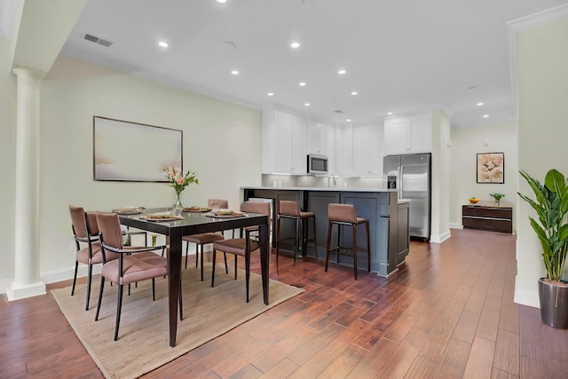 dining room featuring ornamental molding, ornate columns, and dark hardwood / wood-style floors