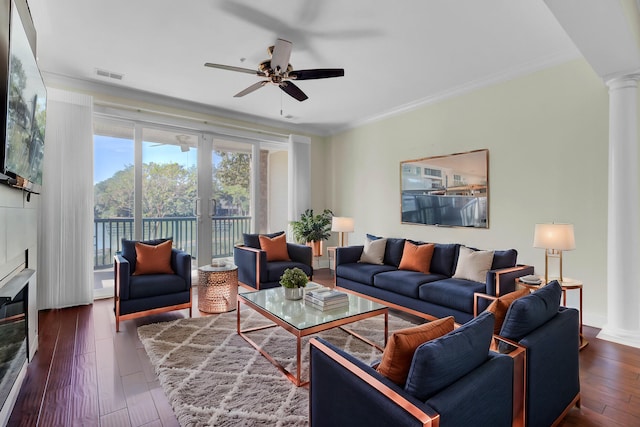 living room featuring decorative columns, dark hardwood / wood-style floors, crown molding, and ceiling fan