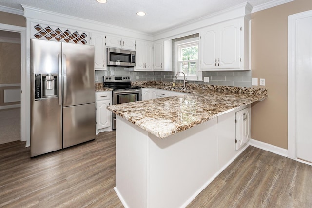 102 Six Point Ct, Goose Creek, SC 29445 - kitchen with stainless steel appliances, wood finished floors, a peninsula, white cabinets, and ornamental molding