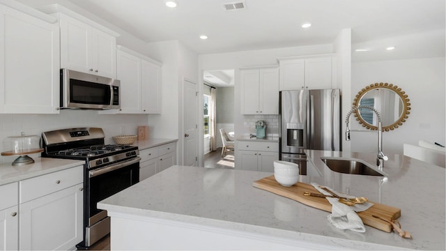 kitchen with white cabinetry, sink, stainless steel appliances, and light stone counters