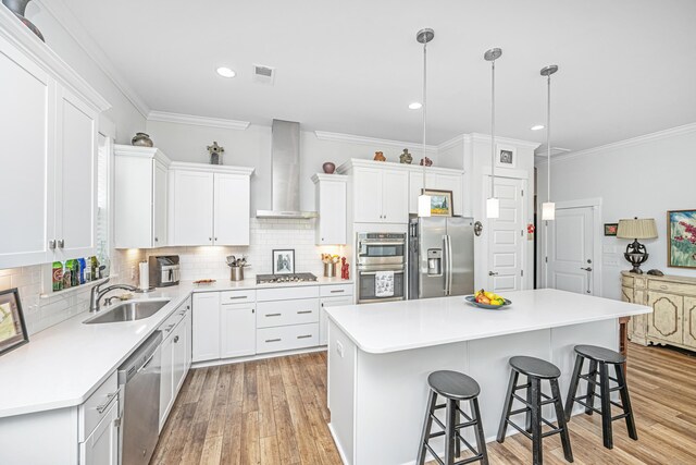 1515 Pogonia St Unit 2, Mount Pleasant, SC 29466 - kitchen featuring stainless steel appliances, a sink, wall chimney range hood, light wood-type flooring, and a kitchen bar