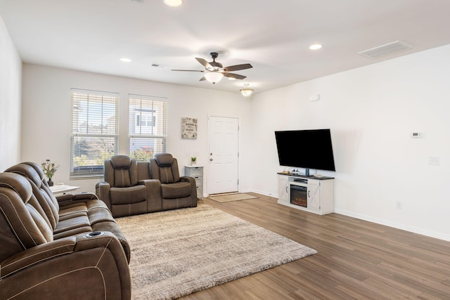 living room with ceiling fan, a fireplace, and wood-type flooring