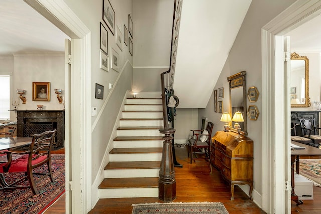 stairway featuring a fireplace, baseboards, and wood-type flooring