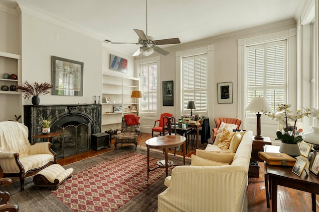 sitting room with ceiling fan, built in features, ornamental molding, and wood finished floors
