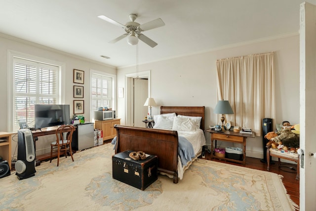 bedroom featuring ceiling fan, ornamental molding, and light wood-style flooring