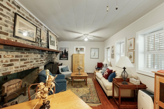 living area with a ceiling fan, ornamental molding, wood finished floors, and a fireplace