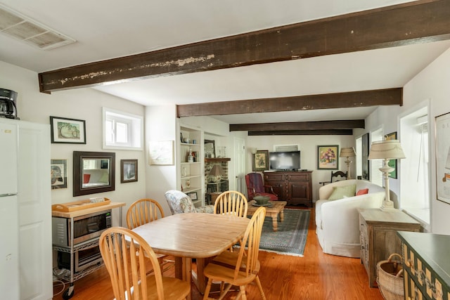 dining area with visible vents, beam ceiling, and wood finished floors