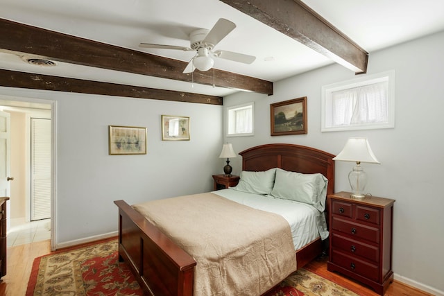 bedroom featuring baseboards, visible vents, beam ceiling, and light wood-style floors