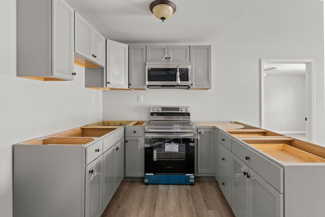 kitchen featuring gray cabinets, appliances with stainless steel finishes, and light hardwood / wood-style flooring