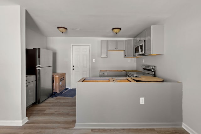 kitchen featuring light wood-type flooring, stainless steel appliances, and gray cabinetry