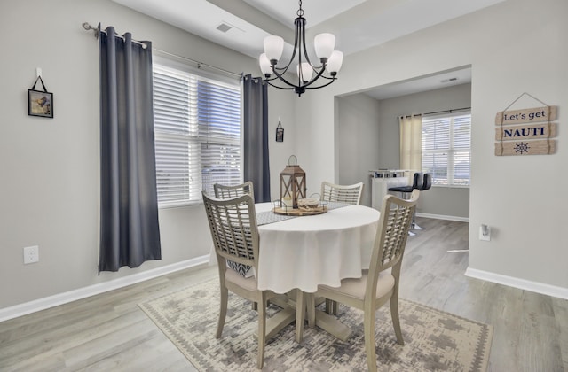 dining space featuring hardwood / wood-style flooring and an inviting chandelier