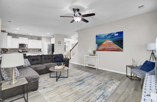 living room featuring ceiling fan, sink, and light wood-type flooring