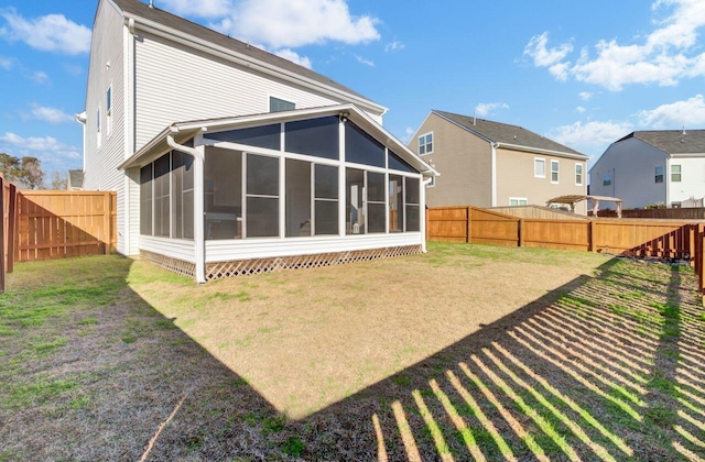 back of property with a lawn and a sunroom