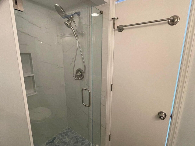 bathroom featuring a shower with shower door and toilet