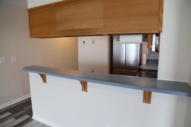 kitchen with dark wood-type flooring, a kitchen breakfast bar, and kitchen peninsula