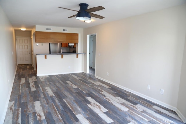 unfurnished living room featuring dark wood-type flooring and ceiling fan