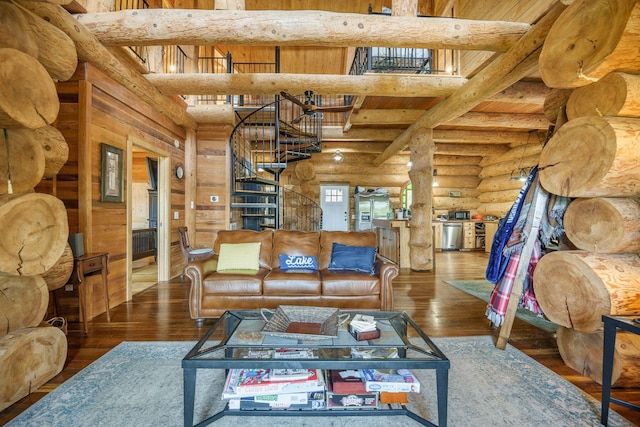living area with rustic walls, hardwood / wood-style flooring, stairway, and beam ceiling