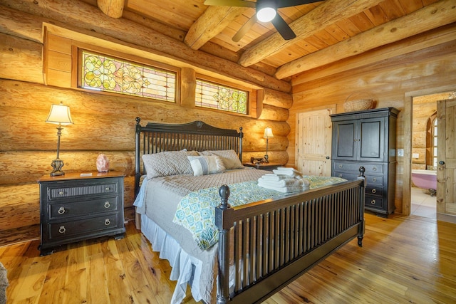 bedroom featuring light wood finished floors, beam ceiling, wooden ceiling, and ensuite bath