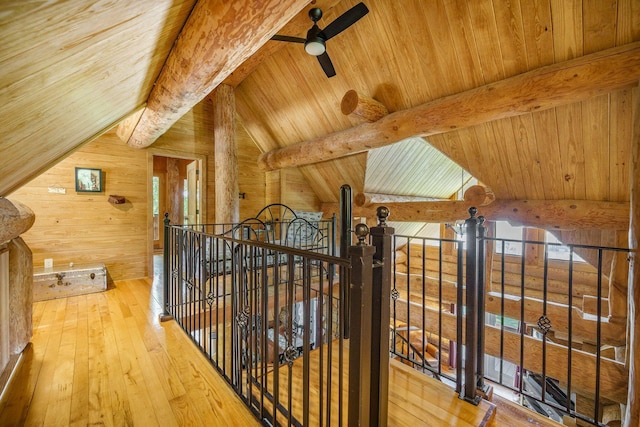 hall with wooden ceiling, hardwood / wood-style floors, wooden walls, and an upstairs landing