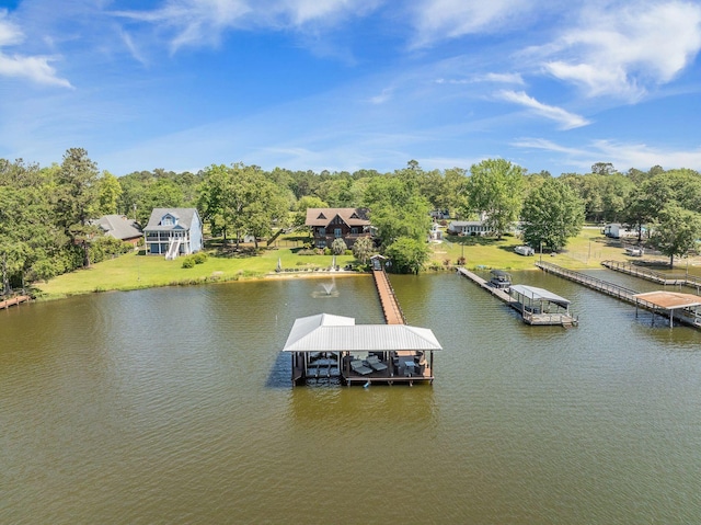 dock featuring a water view, boat lift, view of scattered trees, and a yard