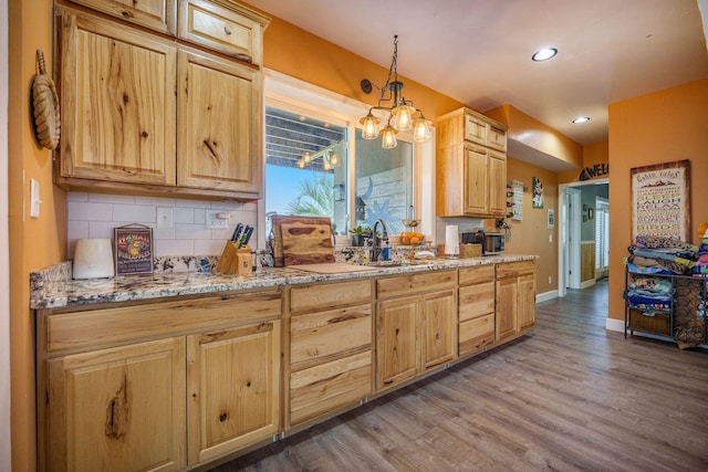 kitchen featuring a sink, light brown cabinetry, wood finished floors, a chandelier, and tasteful backsplash