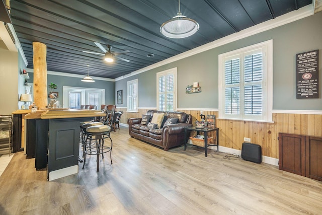 living area with crown molding, a wainscoted wall, plenty of natural light, wood finished floors, and ceiling fan