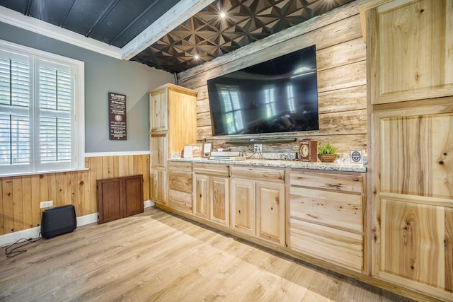 bar area featuring wood walls, light wood-style floors, a wainscoted wall, an ornate ceiling, and crown molding