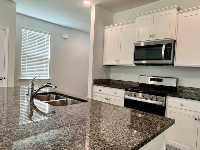 kitchen with dark stone counters, stainless steel appliances, sink, white cabinetry, and a healthy amount of sunlight